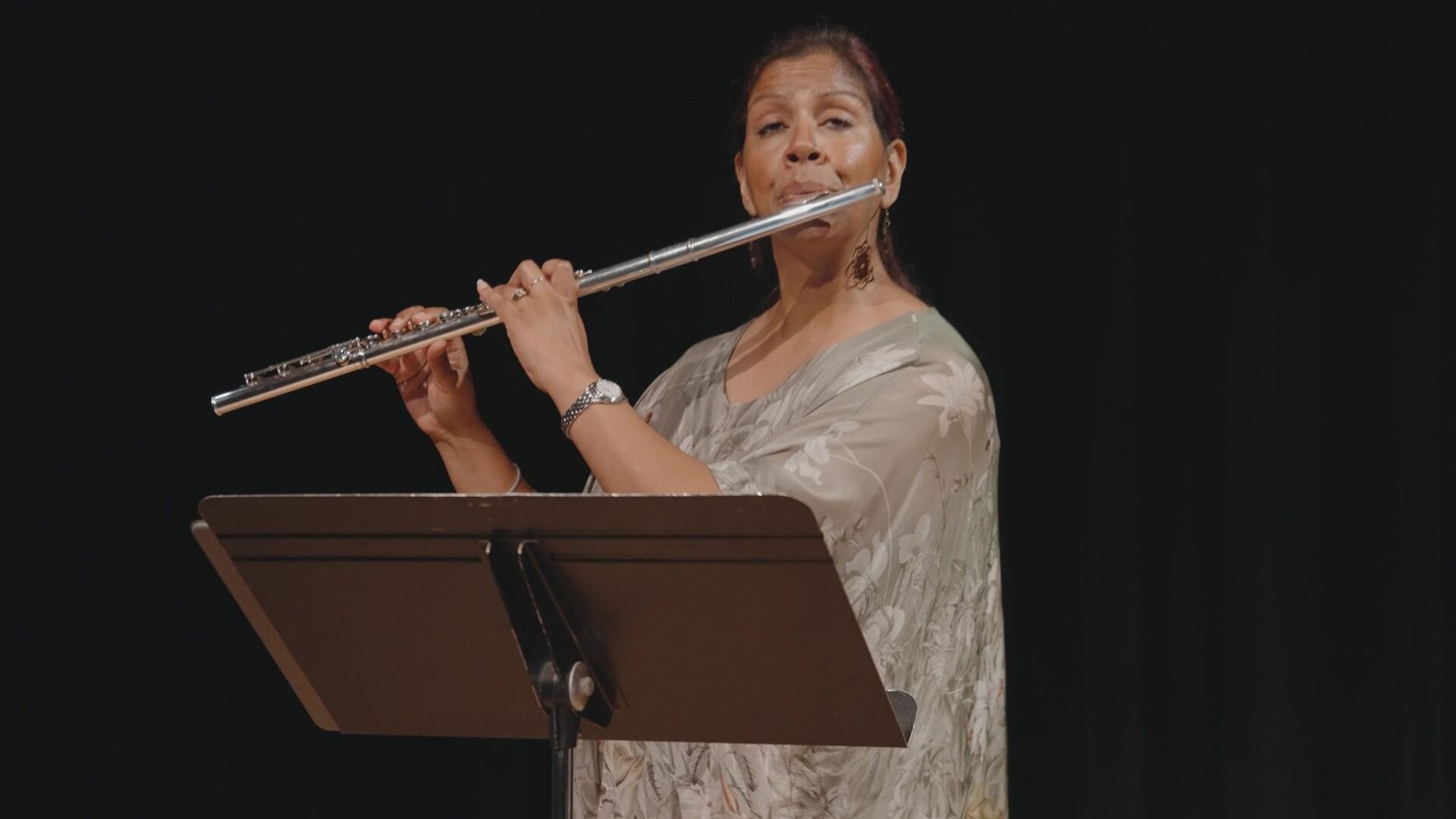 Abha Dearing playing the flute at a music stand